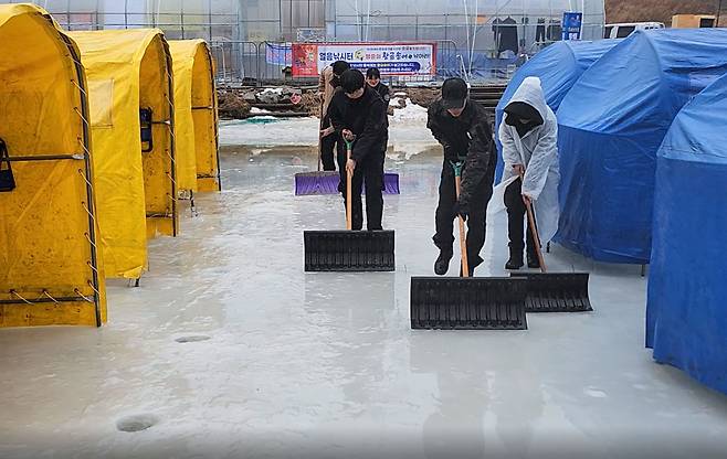 강원 평창군 진부면 오대천 일원 제14회 평창송어축제장이 13일 내린 비로 인해 이날 하루 긴급 휴장하고, 축제 관계자 등이 빗물 제거 작업을 하고 있다./연합뉴스