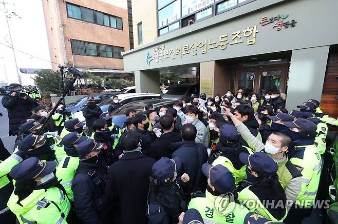 경찰-보건의료노조 실랑이 (서울=연합뉴스) 류영석 기자 = 18일 오후 국정원이 압수수색 중인 서울 영등포구 민주노총 전국보건의료산업노동조합 사무실 입구에서 경찰이 압수수색 종료 때 손팻말 시위를 하려는 노조원들을 막아서고 있다. 2023.1.18 ondol@yna.co.kr