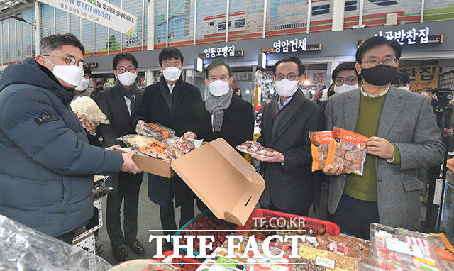 유원식 희망친구 기아대책 회장과 김정기 우리카드 대표이사, 최현만 미래에셋증권 회장, 이복현 금융감독원장, 이재근 KB국민은행장(오른쪽부터)이 시장 상인(왼쪽 첫 번째)과 기념사진을 찍고 있다.