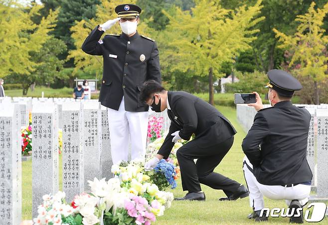 대전 유성구 국립대전현충원에서 의전단이 사전 신청받은 묘역에서 헌화·참배 사진 전송 서비스를 하기 위해 헌화 모습을 촬영하고 있다. 2021.9.14/뉴스1 ⓒ News1 김기태 기자