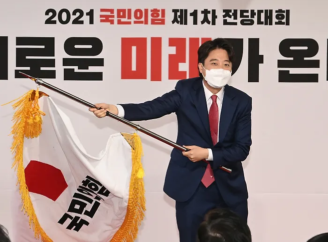 이준석 전 대표가 2021년 6월 국민의힘 당대표로 당선된 전당대회에서 당 깃발을 흔들고 있다. 연합뉴스