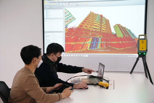 롯데건설 관계자가 3D 스캐너를 활용한 기존 아파트 모델링 데이터를 확인하고 있다.