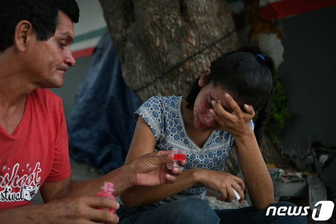 <자료 사진> 멕시코 타마울리파스 마타모로스에서 한 온두라스 이주민 남성이 자신의 17세 딸에게 기침시럽을 먹이고 있다. 2019. 7. 27. ⓒ 로이터=뉴스1 ⓒ News1 최서윤 기자