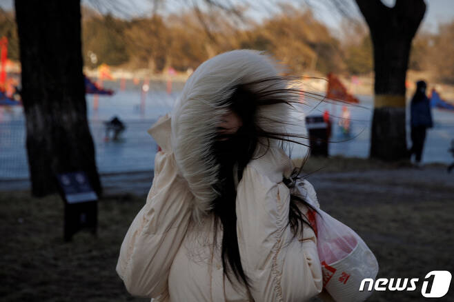 23일(현지시간) 중국 베이징에서 음력설 맞이 축제를 찾은 여성이 강하게 불어오는 바람을 모자로 막고 있다. ⓒ 로이터=뉴스1 ⓒ News1 권진영 기자