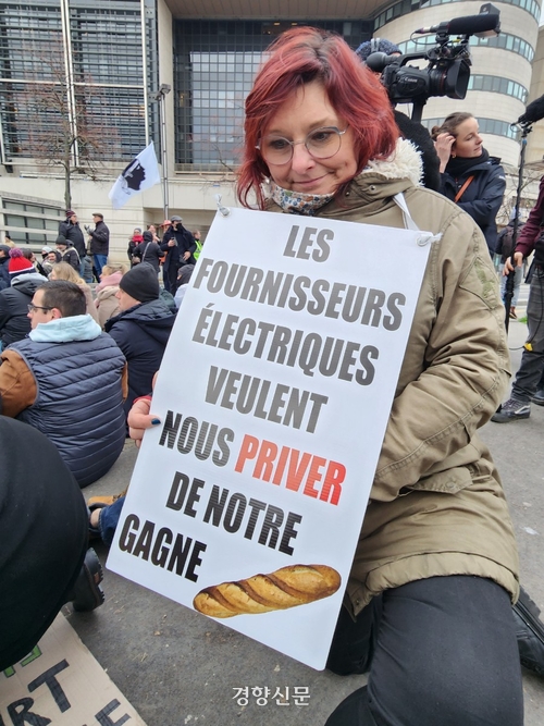 프랑스 서부 오동에서 온 제빵사 마리안이 ‘전기 공급업체들이 우리의 벌이를 빼앗으려 한다’고 적힌 피켓을 들고 앉아 있다.