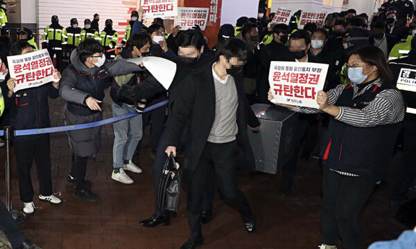 지난 18일 '간첩단 의혹'과 관련해 압수수색을 마친 국가정보원 관계자들이 서울 정동 민주노총에서 압수물품을 들고 나오는 옆으로 민주노총 관계자들이 정권규탄 피켓을 들고 있다. 뉴시스