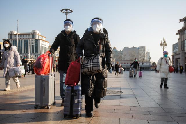 10일 중국 베이징의 베이징역 앞에서 마스크를 착용한 시민들이 수하물과 함께 이동하고 있다. 베이징=AFP 연합뉴스