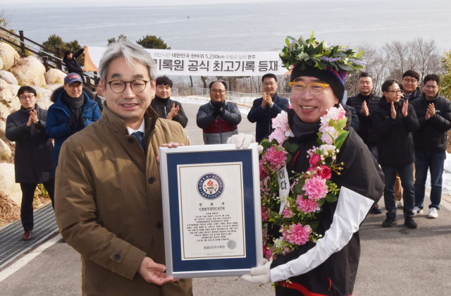 조웅래(오른쪽) 맥키스컴퍼니 회장이 ‘대한민국 한 바퀴 5228㎞’를 국내 최초·최단시간에 완주한 뒤 인증패를 받고 있다. 사진제공=맥키스컴퍼니