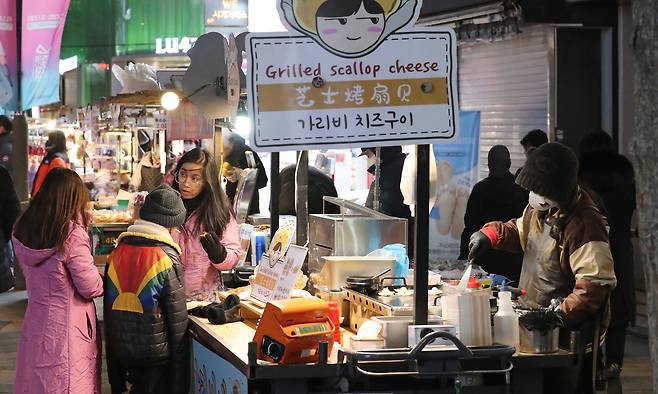 20일 오후 서울 명동 가리비 치즈구이 노점을 찾은 외국인 관광객 가족이 요리를 기다리는 모습. /남강호 기자