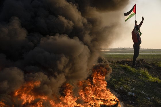 팔레스타인 사람들이 제닌 난민촌에 대한 이스라엘군의 공격을 항의하며 타이어를 불태우고 국기를 흔들고 있다. AP=연합뉴스