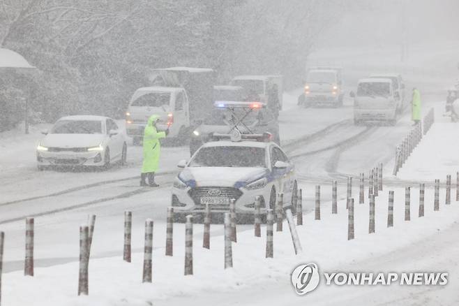 폭설에 제주 산간도로 통제 (서귀포=연합뉴스) 박지호 기자 = 제주도 산지에 대설경보가 내려진 27일 오후 서귀포시 516도로 입구에서 경찰이 교통을 통제하고 있다. 2023.1.27 jihopark@yna.co.kr