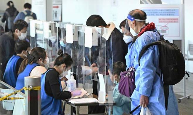 지난 8일 중국 상하이발 승객들이 일본 수도 도쿄 인근 나리타공항에 도착 직후 코로나19 음성 판정을 받은 증명서를 제시하고 있다. 나리타=교도·AP뉴시스