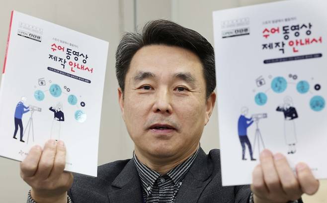 이규승 대전 동구보건소 전문경력관이 수어 동영상 제작 안내서를 들고 기념촬영을 하고 있다.  대전 동구 제공