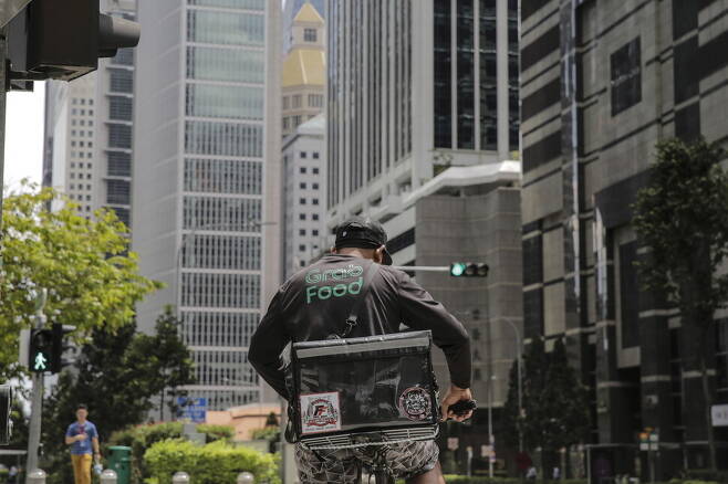 배달플랫폼 ‘그랩’ 배달원이 지난 2020년 싱가포르 금융가의 한 건널목 앞에서 진행 신호를 기다리고 있다. EPA 연합뉴스