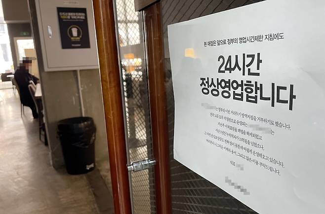 지난 2021년 12월21일 인천 한 카페 출입문에 정부 영업제한 조치를 거부하고 24시간 영업을 강행한다는 내용의 안내문이 부착돼 있다./연합뉴스