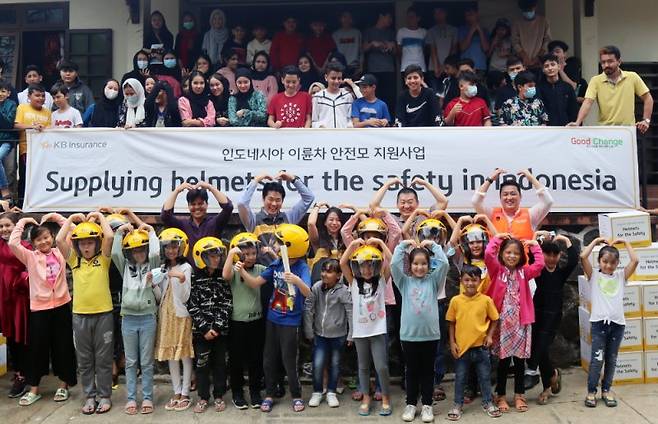 KB손해보험이 지난 6일 인도네시아의 한 학교에서 개최한 이륜차 안전모 전달 행사에서 KB손해보험 인도네시아법인 직원과 학생들이 기념촬영을 하고 있다.