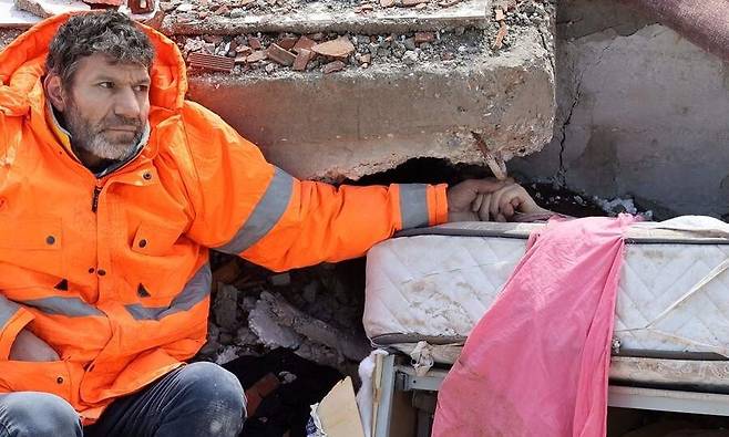 7일 튀르키예 남동부 카흐라만마라시에서 메수트 한제르가 지진으로 무너진 아파트 잔해에 깔린 15살 숨진 딸의 손을 놓지 못하고 있다. AFP 연합뉴스