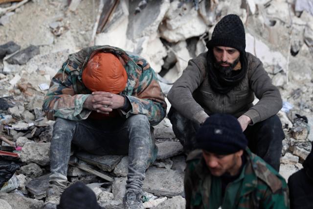 7일 시리아 알레포에서 주민들이 지진으로 무너진 건물 잔해 위에 침울한 표정으로 앉아 있다. 알레포=AP 뉴시스