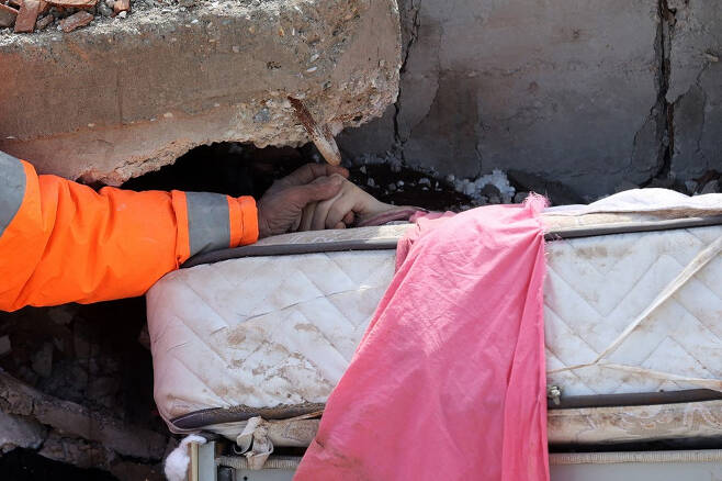 7일(현지시간) 튀르키예 카라만마라스에서 주민 메수트 한세르가 건물에 깔린 15살 딸의 손을 꼭 잡고 있다. 딸은 결국 사망했다./AFPBBNews=뉴스1