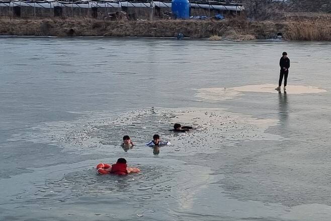 지난 8일 오후 빙판 위에서 물에 빠진 학생들을 소방관들이 구조하고 있다./뉴스1