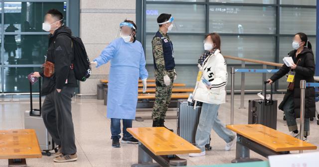 9일 인천국제공항 제1여객터미널에서 방역 관계자가 중국에서 입국한 승객들을 안내하고 있다. 연합뉴스