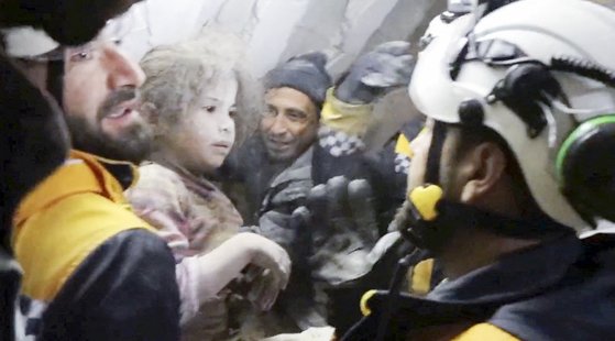 지진 피해가 큰 시리아 잔다리스 지방에서 긴급 구조 활동을 펴고 있는 인도주의 봉사단체 ‘하얀 헬멧’ 구조대원들이 8일(현지시간) 무너진 건물 사이에 갇힌 한 여자아이를 구출한 뒤 안고 있다. 로이터=연합뉴스