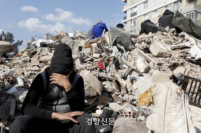 튀르키예 강진 5일째인 10일(현지시간) 튀르키예 안타키아에서 한 주민이 폐허로 변한 붕괴 건물 잔해 앞에서 얼굴을 감싸쥐고 앉아 있다.  안타키아(튀르키예)｜문재원 기자