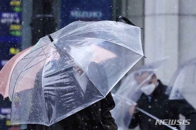 [도쿄=AP/뉴시스] 일본 수도 도쿄 시내에서 10일 싸리눈이 내리는 가운데 우산을 펴든 시민들이 걸어가고 있다. 2023.02.11