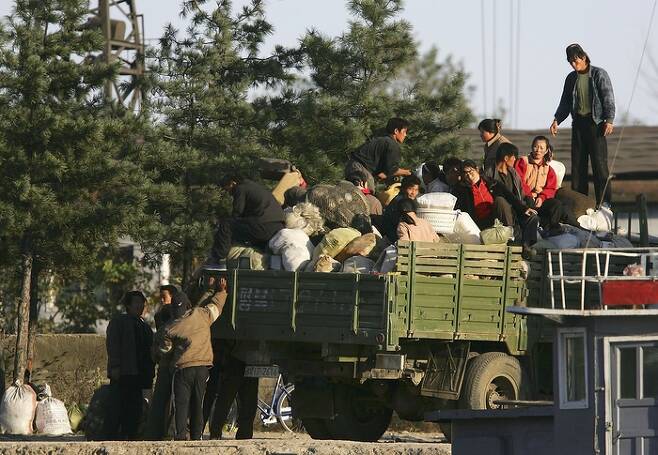 2006년 10월 신의주 부두에서 화물을 트럭에 싣고 있는 북한 주민들. 고난의 행군 이후 본격화된 시장화 과정에서 여성들의 경제행위가 두드러졌다. 게티이미지