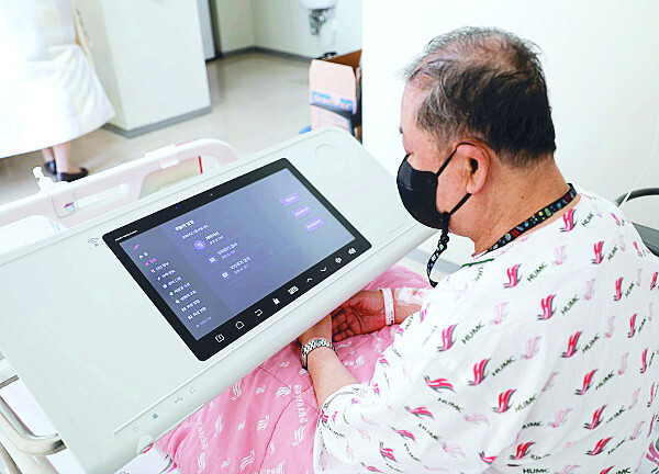 4인실 입원 환자가 침상에 설치된 태블릿PC를 활용하는 장면.