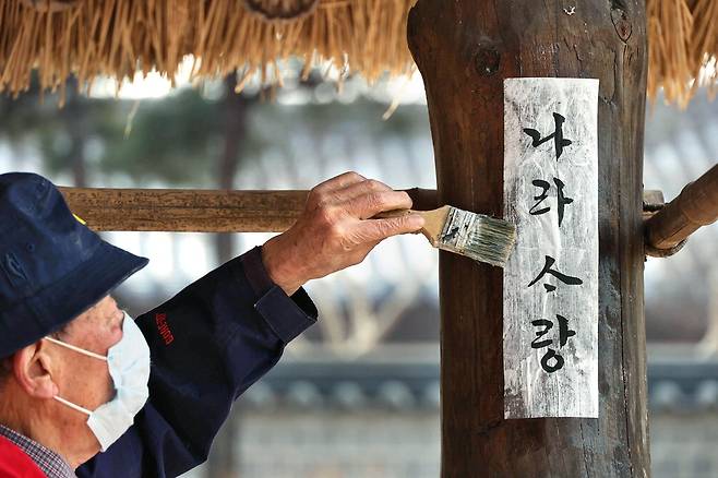 한 어르신이 서울 남산골한옥마을 쉼터 기둥에 '나라사랑'이라 쓴 종이를 붙이고 있습니다. 모든 사랑은 표현할 때 더 아름답지 않을까요.  <이충우 기자>