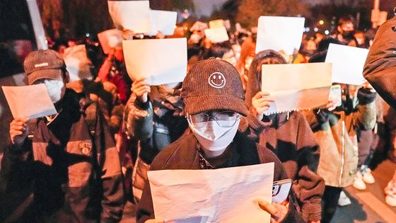 지난달 27일 중국 베이징에서 시위대가 당국의 제로 코로나 정책에 항의하는 의미로 백지를 들고 시위를 하고 있다. AP=연합뉴스