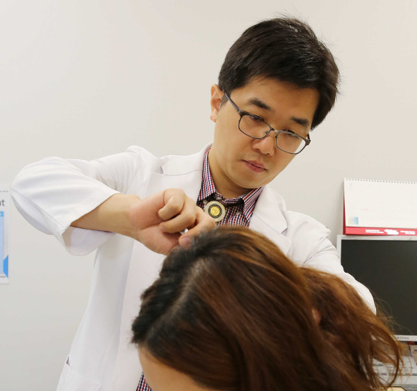 순천향대부천병원 정문영 교수가 난치성 두통으로 병원을 찾은 여성 환자의 머리 뒤쪽 후두신경 부위를 살펴보고 있다. 순천향대부천병원 제공