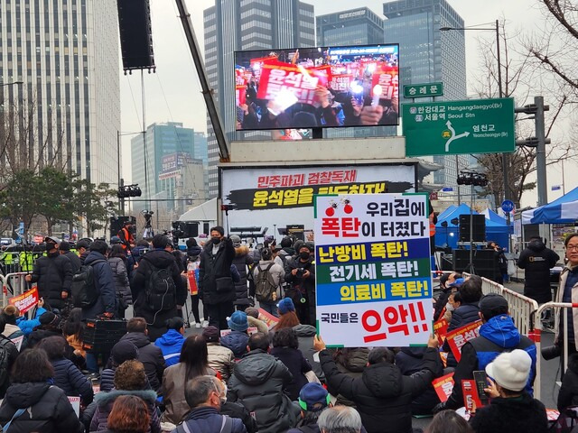 18일 오후 5시께 ‘김건희 특검·윤석열 퇴진 전국집중 촛불 대행진(26차)’에서 한 참가자가 ‘우리집에 폭탄이 터졌다. 난방비·전기세·의료비 폭탄! 국민들은 으악!!’이라고 쓰인 손팻말을 들고 있다. 고병찬 기자