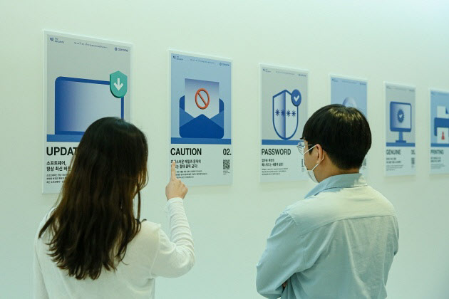 코인원 임직원들이 본사에 게시된 생활 보안 777캠페인 포스터를 보고 있다.(사진=코인원)