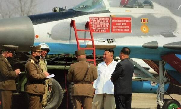 김정은 북한 국무위원장이 수행원들과 함께 미그-29 전투기 앞에서 대화를 나누고 있다. 조선중앙TV·뉴스1