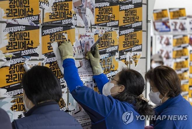 지난달 27일 서울 삼각지역에서 서울교통공사 관계자들이 전국장애인차별철폐연대(전장연)가 부착한 전단을 떼고 있다.<자료=서울시>