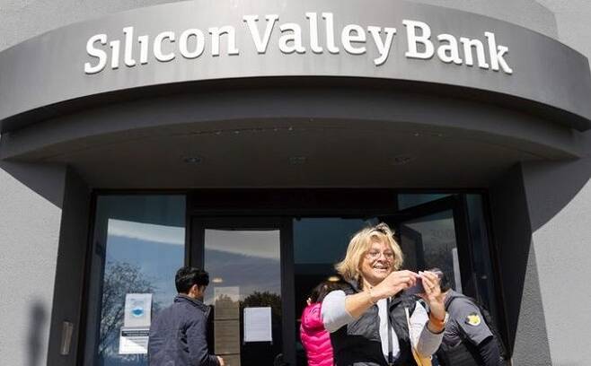 13일(현지시간) 미 캘리포니아주 샌타클래라 실리콘밸리은행(SVB) 본점 앞에서 예금 인출을 위해 대기하다가 입장하게 된 여성이 셀카를 찍고 있다. ⓒ AP/뉴시스