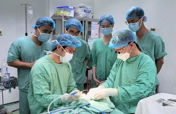 부산대병원 배용찬(오른쪽) 교수가 이번 의료봉사 기간 베트남에서 구순구개열 어린이 환자를 수술하며 현지 의료진에게 수술법을 가르쳐주고 있다.