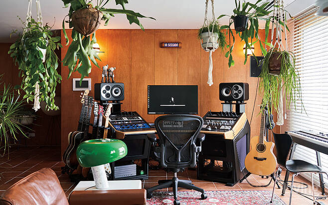 원목 벽과 음향기기, 식물이 어우러져 오래된 녹음실 분위기를 풍기는 작업실.