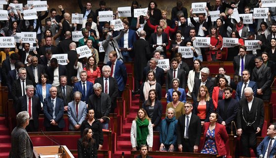 16일(현지시간) 프랑스 하원에서 엘리자베스 보른 총리가 연금 개혁안의 의회 무투표 강행에 대한 연설을 하고 있다. 야당 의원들은 '64세를 반대한다'는 종이를 들고 기립해 야유했다. AFP=연합뉴스