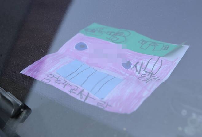 지난 18일 인천시 미추홀구 한 주택에서 숨진 채 발견된 일가족 소유 차량에 아이가 쓴 것으로 보이는 쪽지가 놓여 있다. /연합뉴스