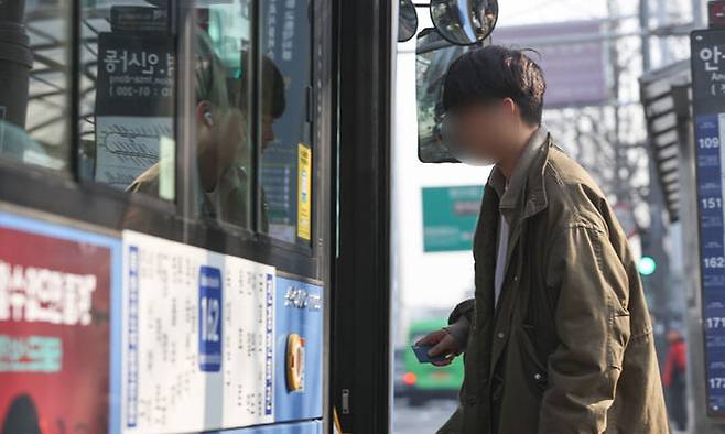 대중교통 내 마스크 착용 의무가 해제된 20일 서울 시내 한 버스정류장에서 한 시민이 마스크를 벗고 버스에 탑승하고 있다. 연합뉴스