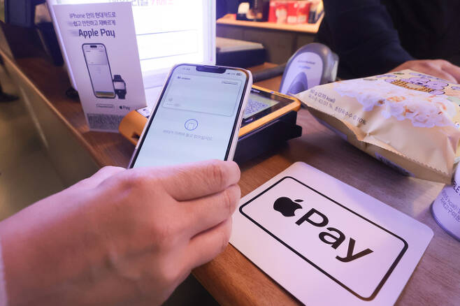 애플의 근거리무선통신(NFC) 결제 서비스 ‘애플페이’ 서비스 개시일인 21일 서울 용산구 이마트24 R한남제일점에서 한 시민이 애플페이로 상품을 결제하고 있다. [연합뉴스]