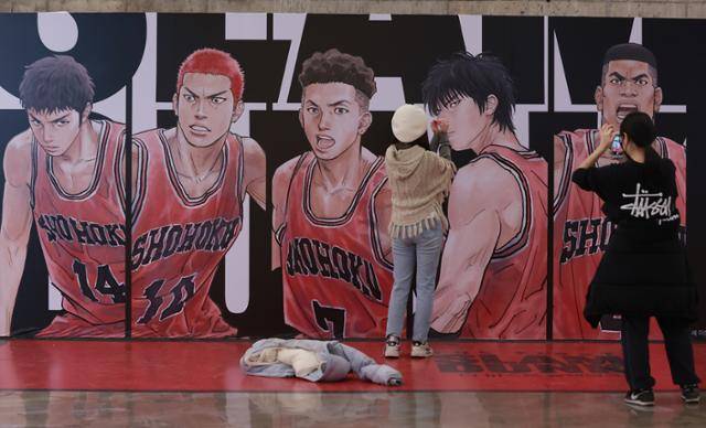 영화 '더 퍼스트 슬램덩크' 홍보물 앞에서 인증 사진을 찍고 있는 사람들. 연합뉴스