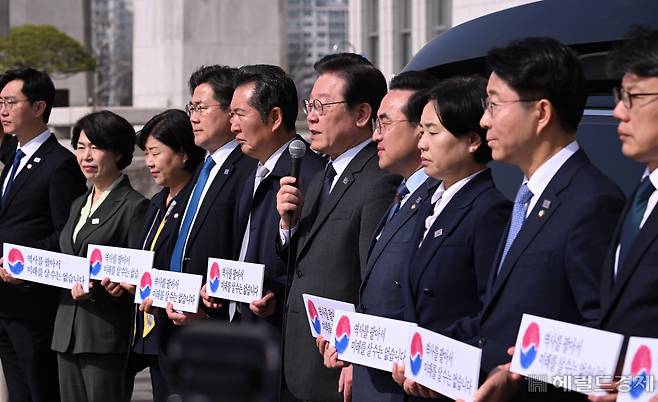 더불어민주당 대일굴종외교 규탄 태극기달기 운동 행사가 22일 서울 영등포구 여의도 국회 본청 앞에서 열려 이재명 대표를 비롯한 지도부가 참석해 기자회견 및 태극기 부착행사를 진행하고 있다. 임세준 기자