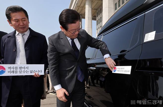 더불어민주당 대일굴종외교 규탄 태극기달기 운동 행사가 22일 서울 영등포구 여의도 국회 본청 앞에서 열려 이재명 대표가 '역사를 팔아서 미래를 살 수는 없습니다' 문구가 담긴 태극기 스티커를 차량에 붙이고 있다. 임세준 기자
