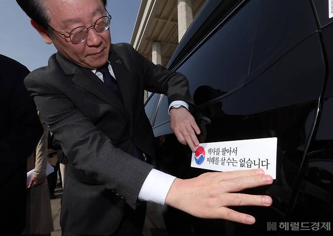 더불어민주당 대일굴종외교 규탄 태극기달기 운동 행사가 22일 서울 영등포구 여의도 국회 본청 앞에서 열려 이재명 대표가 '역사를 팔아서 미래를 살 수는 없습니다' 문구가 담긴 태극기 스티커를 차량에 붙이고 있다. 임세준 기자