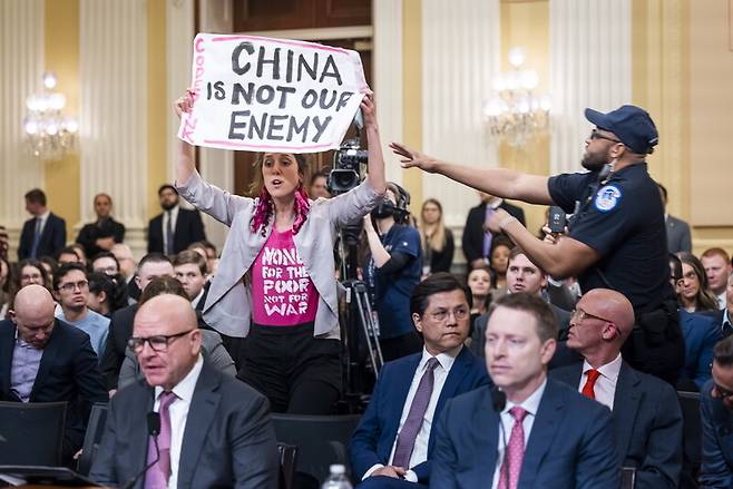 지난달 28일 미국 하원의 ‘미국과 중국공산당의 전략적 경쟁에 관한 특별위원회’가 개최한 청문회에서 허버트 맥매스터 전 백악관 국가안보보좌관(앞줄 왼쪽)이 발언하는 가운데 방청객이 ‘중국은 우리 적이 아니다’라고 쓴 종이를 들고 항의하다가 제지당하고 있다. 워싱턴/EPA 연합뉴스