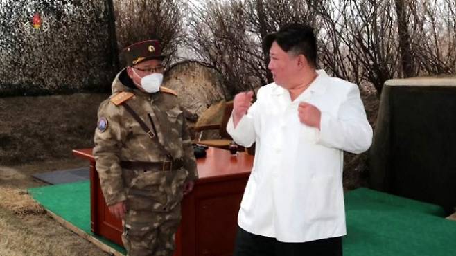 김정은 북한 국무위원장(오른쪽)이 22일 전략순항미사일 핵탄두 모의 공중폭발 시험 현장에서 권투선수처럼 두 주먹을 불끈 쥐어 보이고 있다. 조선중앙TV·연합뉴스